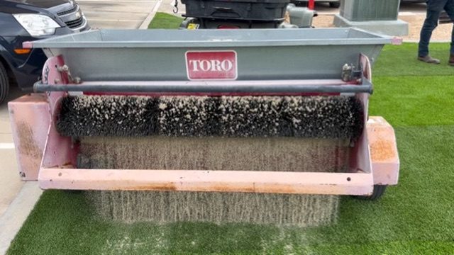 Toro machine brushing and spreading infill onto newly installed artificial turf