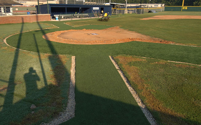 Artificial grass around a baseball infield seen from the dugout