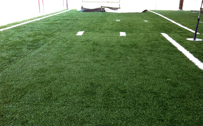 Outdoor hitting area surfaced with artificial grass and white field lines